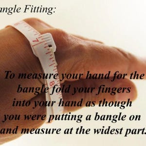 May include: A hand with a measuring tape wrapped around the wrist. The text reads: "Bangle Fitting: To measure your hand for the bangle fold your fingers into your hand as though you were putting a bangle on and measure at the widest part."