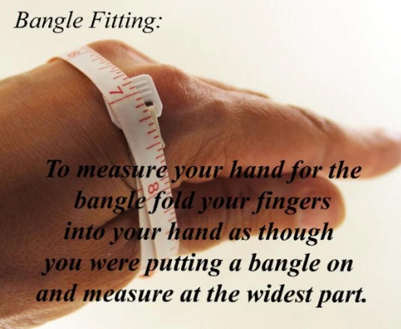 May include: A hand with a measuring tape wrapped around the wrist. The text reads: "Bangle Fitting: To measure your hand for the bangle fold your fingers into your hand as though you were putting a bangle on and measure at the widest part."