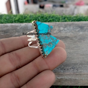 May include: A silver ring featuring a large, triangular turquoise stone with brown matrix patterns. The ring has a unique design with multiple bands and a jagged edge around the stone. The text "BalajiJewellersGifts" is visible.