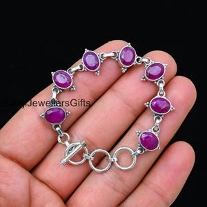 Può includere: Un braccialetto d'argento con chiusura a scorrimento presenta pietre preziose rosa di forma ovale incastonate in argento.