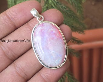 Op de afbeelding: Ovale hanger met een zilverkleurig frame. De hanger heeft een gepolijste, iriserende steen met roze en witte tinten. De tekst "BalajiJewellersGifts" is zichtbaar aan de linkerkant. De hanger wordt in een hand gehouden.