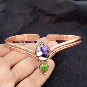 Op de afbeelding: Koperkleurige armband met een centrale druppelvormige steen met paarse, witte en groene accenten. De armband heeft een textuurontwerp en de tekst "BalajiJewellersGifts".