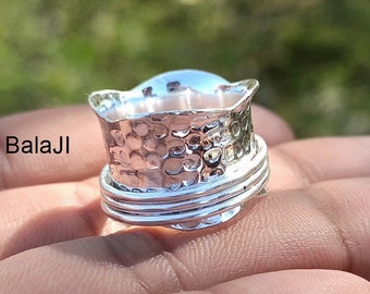 May include: A silver spinning ring with a hammered texture and three bands. The ring is worn on a finger.