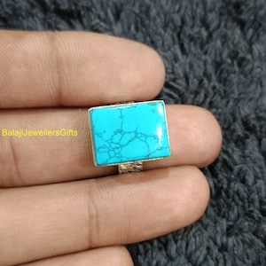May include: A silver ring featuring a square turquoise stone. The stone is light blue in colour and has a marbled pattern.