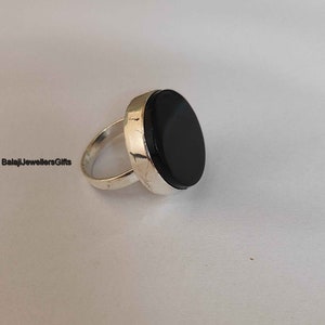 May include: A silver ring with a large, round, black onyx stone.