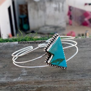 May include: A silver cuff bracelet with a triangular turquoise stone and a beaded edge. The bracelet has a three-strand design. The text "BalajiJewellersGifts" is visible.