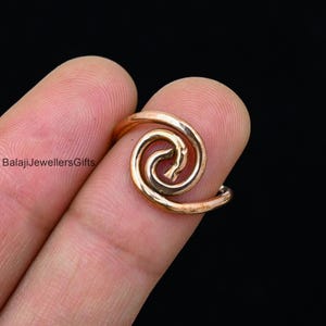 May include: A copper spiral ring with a hammered finish. The ring is open and adjustable to fit most finger sizes.