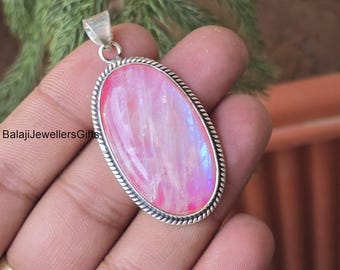 Op de afbeelding: Ovale hanger met een roze en iriserende steen, gezet in een zilverkleurig metalen frame. De hanger heeft een getextureerde rand en een kleine lus aan de bovenkant voor een ketting. De tekst "BalajiJewellersGifts" is zichtbaar.