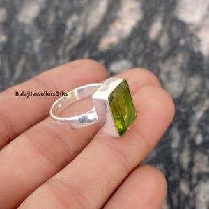 Könnte beinhalten: Ein Silberring mit einem rechteckigen, hellgrünen Edelstein. Der Ring hat ein schlichtes Band und eine quadratische Fassung für den Edelstein. Der Text "BalajiJewellersGifts" ist auf dem Ring zu sehen.