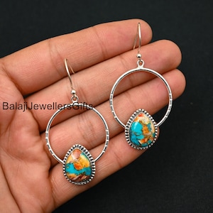 Könnte beinhalten: Silberne Creolen mit tropfenförmigen Anhängern aus türkis-, orange- und braunfarbenen Steinen. Die Ohrringe werden vor schwarzem Hintergrund präsentiert. Der Text "Balaji Jewellers Gifts" ist sichtbar.