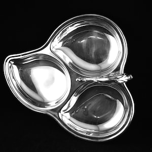 Puede incluir: Un plato de servir de plata con tres compartimentos separados. El plato tiene un asa decorativa.