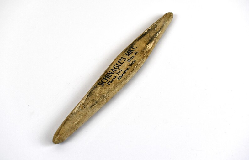 May include: A vintage wooden tool with a tapered shape, likely used for a specific craft or trade. The tool has a worn, aged appearance with visible wear and tear. The text "SCHINAGLE'S MKT." is printed on the side.