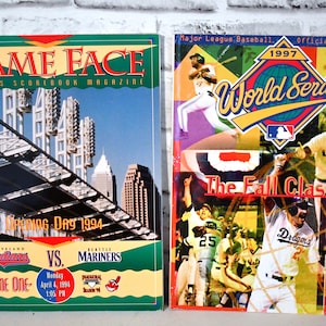 Könnte beinhalten: Zwei Baseball-Spielprogramm-Cover. Das linke Cover ist grün und zeigt ein Foto eines Stadions mit dem Text "GAME FACE" und "Opening Day 1994". Das rechte Cover ist bunt und zeigt ein Foto von Baseballspielern mit dem Text "1997 World Series" und "The Fall Classic".
