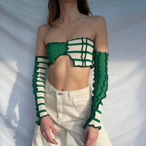 May include: A green and white striped off-the-shoulder top with ruffled edges. The top is made of a soft, stretchy fabric and has a cropped fit.
