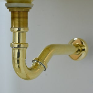Puede incluir: Un tubo de desagüe de lavabo de baño de latón con una curva de 90 grados.