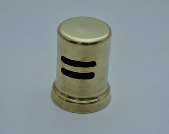 May include: A gold-colored metal drain cover with two rectangular openings. The cover has a smooth, polished finish.