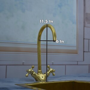 May include: A gold-toned kitchen faucet with two handles and a curved spout. The faucet is 11.5 inches tall and 6 inches wide.
