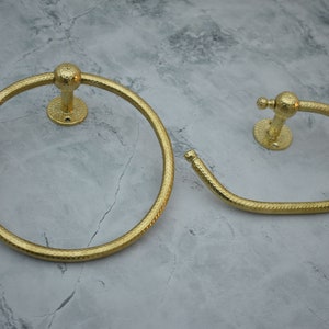 May include: Two gold-toned towel rings with a textured finish. The rings are mounted on a wall.