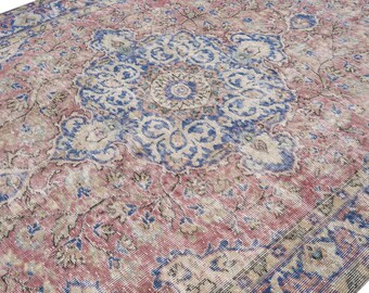 May include: An antique rug with a distressed, faded appearance. The rug features a central medallion design in shades of blue and cream, surrounded by a field of muted red and pink tones. The intricate patterns and color palette suggest a vintage or traditional style.