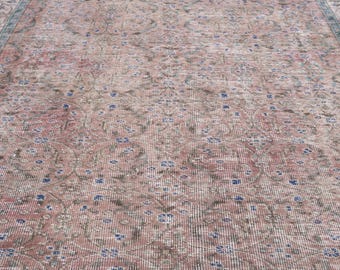 May include: A vintage rug with a distressed, faded appearance. The rug features a repeating floral pattern in shades of pink, brown, and blue. The design has a traditional, oriental style, with a border in a darker shade of blue.