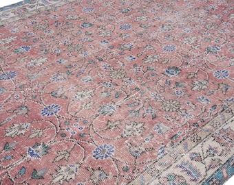 May include: A vintage area rug with a distressed, faded appearance. The rug features a repeating floral pattern in shades of red, blue, and cream. The design includes stylized flowers and vines, with a border in a complementary color palette.