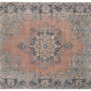 May include: A rectangular, distressed-look rug with a central medallion design. The rug features a faded rose-colored field with a large, ornate floral pattern in the center. The border is dark blue with floral and paisley motifs.