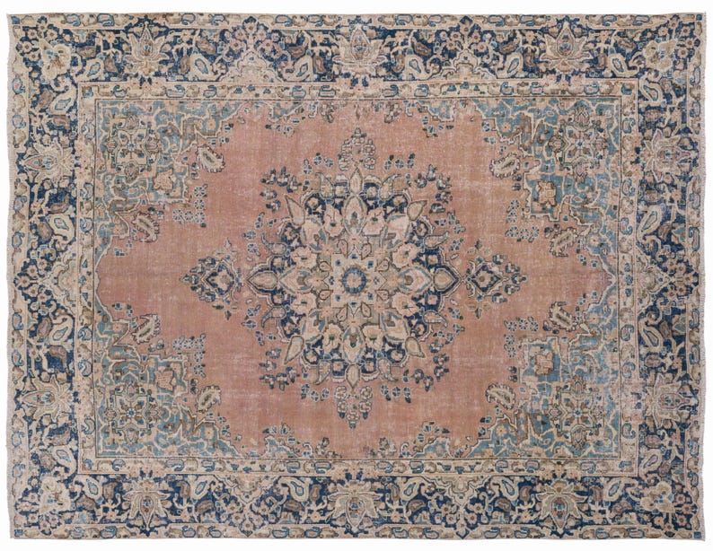 May include: A rectangular, distressed-look rug with a central medallion design. The rug features a faded rose-colored field with a large, ornate floral pattern in the center. The border is dark blue with floral and paisley motifs.