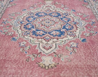May include: A vintage rug with a distressed, faded appearance. The rug features a central medallion design in shades of pink, blue, and cream, with intricate floral and geometric patterns. The rug's dimensions are not visible in the image.
