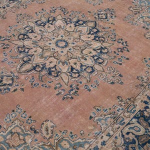 May include: A large, distressed area rug with a central medallion design. The rug features a faded, muted color palette of rose, navy blue, and cream. The intricate floral and geometric patterns create a vintage aesthetic, suitable for living rooms or bedrooms.