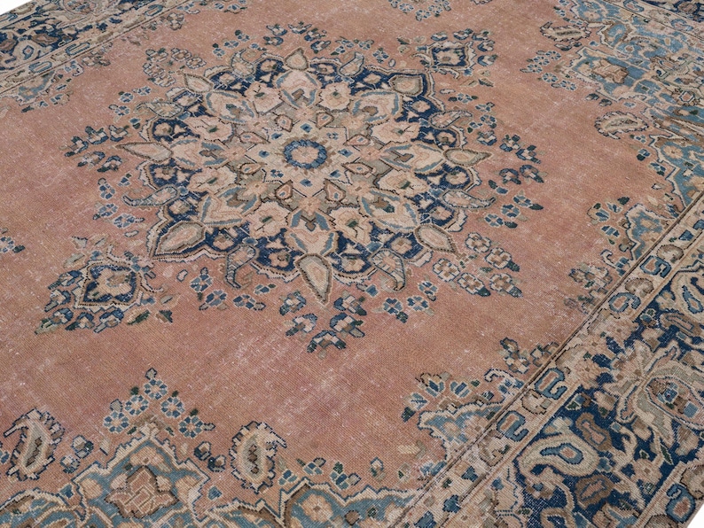 May include: A large, distressed area rug with a central medallion design. The rug features a faded, muted color palette of rose, navy blue, and cream. The intricate floral and geometric patterns create a vintage aesthetic, suitable for living rooms or bedrooms.
