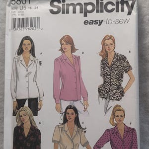 Peut inclure: Une pochette de patron de couture Simplicity 5801 pour les tailles U5 16-24. L'emballage en papier blanc présente des illustrations de six styles de chemisiers différents étiquetés A à F, incluant des couleurs unies, un motif zébré, floral et à pois.