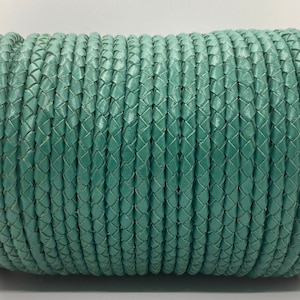 May include: A roll of teal braided leather cord. The cord is tightly wound and has a smooth, polished finish.