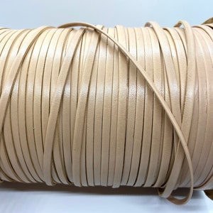 May include: A spool of beige leather cord, wound tightly in a coil.