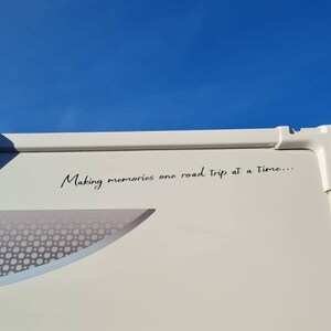 K&ouml;nnte beinhalten: Ein wei&szlig;er Wohnwagen mit dem Text "Making memories one road trip at a time..." an der Seite.