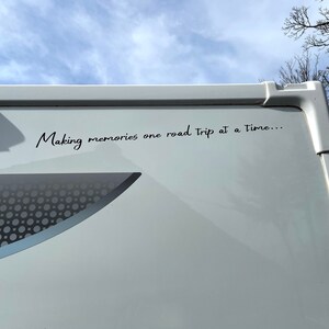 K&ouml;nnte beinhalten: Ein wei&szlig;er Wohnwagen mit dem Text "Making memories one road trip at a time..." an der Seite.