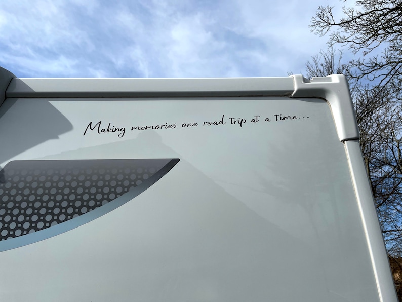 K&ouml;nnte beinhalten: Ein wei&szlig;er Wohnwagen mit dem Text "Making memories one road trip at a time..." an der Seite.