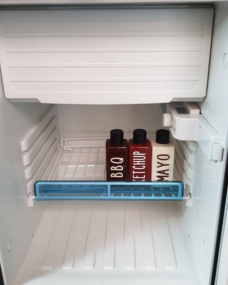 May include: Three condiment bottles in a white refrigerator. The bottles are labeled "BBQ", "Ketchup", and "Mayo".
