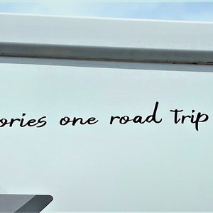 K&ouml;nnte beinhalten: Ein wei&szlig;er Wohnwagen mit dem Text "Making memories one road trip at a time..." in schwarzer Kursivschrift an der Seite.