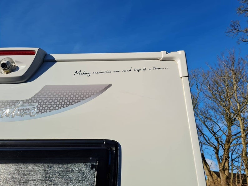 K&ouml;nnte beinhalten: Ein wei&szlig;er Wohnwagen mit dem Text "Making memories one road trip at a time..." an der Seite.