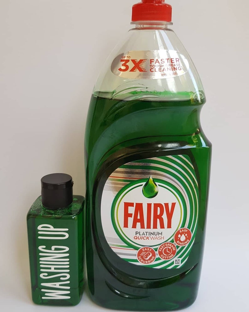 May include: Two bottles of Fairy Platinum Quick Wash dish soap. The larger bottle is green and has a red cap. The smaller bottle is green and has a black cap. The larger bottle has a label that says "Up to 3X Faster Tough Grease Cleaning". The smaller bottle has a label that says "Washing Up".