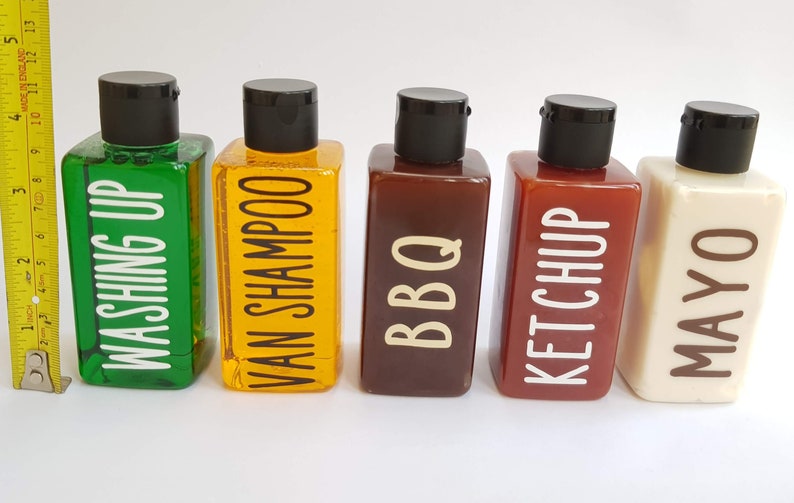 May include: Five clear plastic bottles with black caps and white labels. The labels read "Washing Up", "Van Shampoo", "BBQ", "Ketchup", and "Mayo".