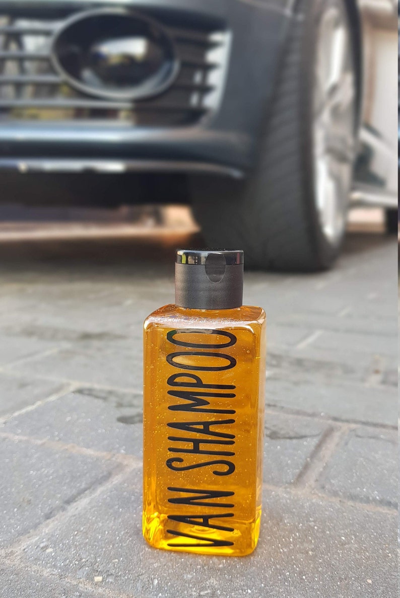 May include: A clear bottle of yellow shampoo with a black cap and the text "VAN SHAMPOO" printed on the bottle.