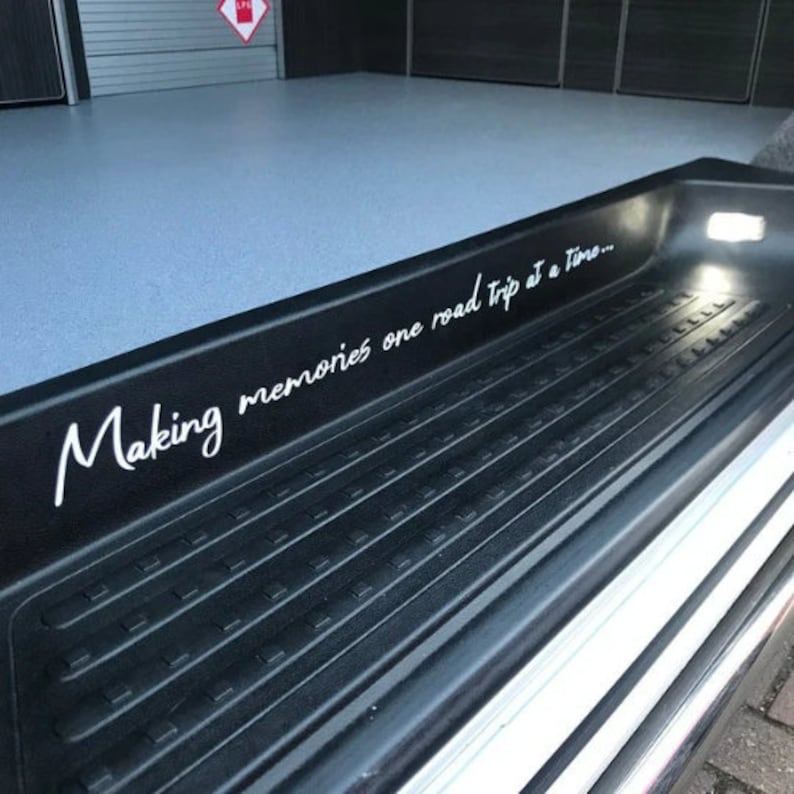 K&ouml;nnte beinhalten: Eine schwarze Stufe mit einer strukturierten Oberfl&auml;che und einer wei&szlig;en Aufschrift, die lautet "Making memories one road trip at a time..."