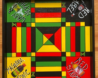 Pode incluir: Um tabuleiro de jogo de madeira com uma moldura preta e um padrão geométrico colorido. O tabuleiro é dividido em quadrados com cores alternadas de vermelho, amarelo, verde e preto. Os quadrados são decorados com imagens de garrafas de álcool, incluindo Red Stripe, Wray & Nephew e Magnum Tonic Wine.
