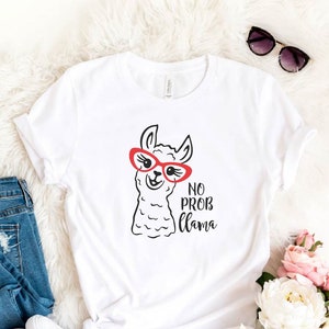 May include: White t-shirt with a cartoon llama wearing red sunglasses and the text "No Prob Llama".