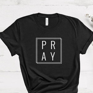 May include: Black t-shirt with a white square and the word "PRAY" inside.