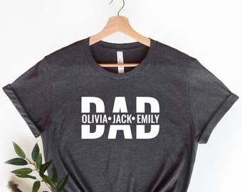 May include: Heather dark grey t-shirt with the word "DAD" in white letters. The names "Olivia", "Jack", and "Emily" are written in smaller white letters below the word "DAD".