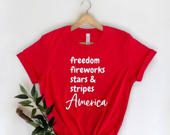 May include: Red t-shirt with white text that reads "freedom fireworks stars & stripes America".