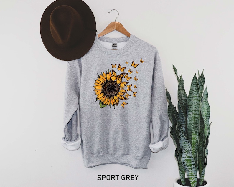 May include: A gray sweatshirt with a sunflower and butterflies printed on the front. The text 'SPORT GREY' is printed below the image.