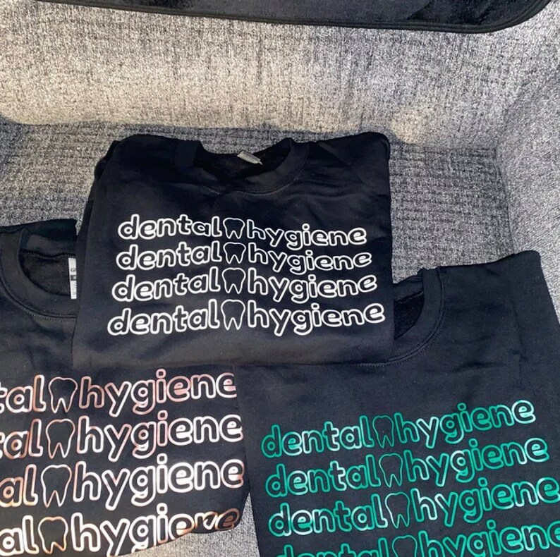 May include: Four black sweatshirts with the text "dental hygiene" printed in white, rose gold, and green. The text is repeated four times on each sweatshirt.